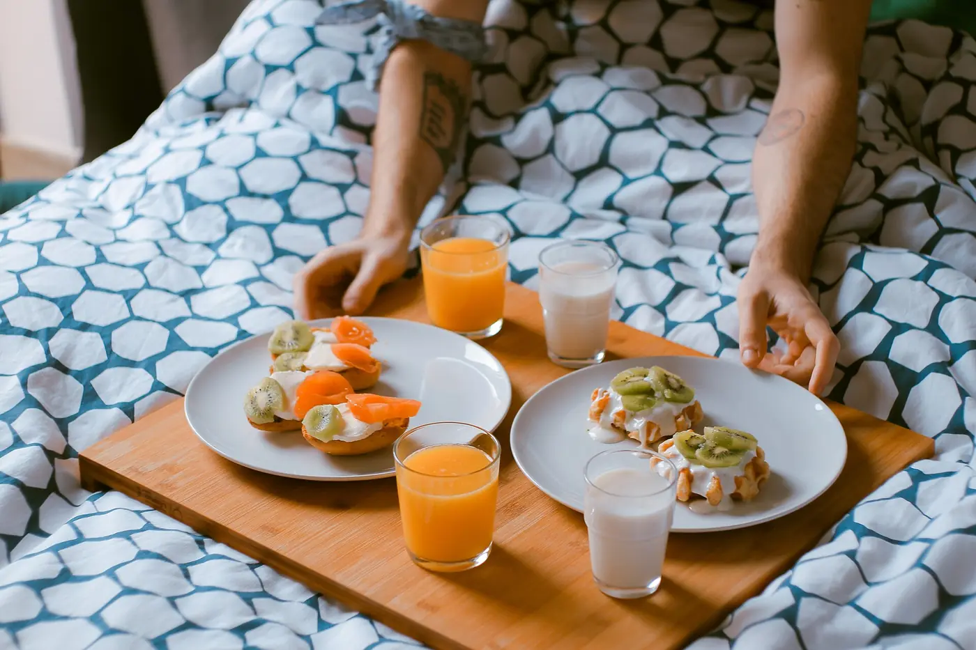 Desayuno servido en charola de madera sobre una cama
