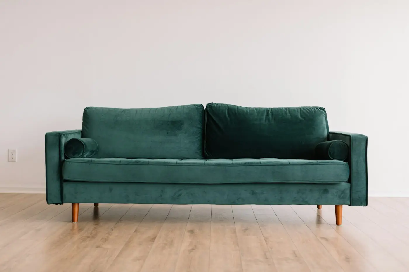 Sofá de terciopelo verde en una sala luminosa